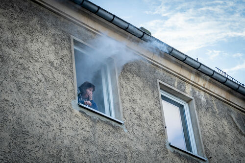 Rauch dringt aus einem Fenster an der Gebäuderückseite. Die Drehleiter wird in Stellung gebracht.